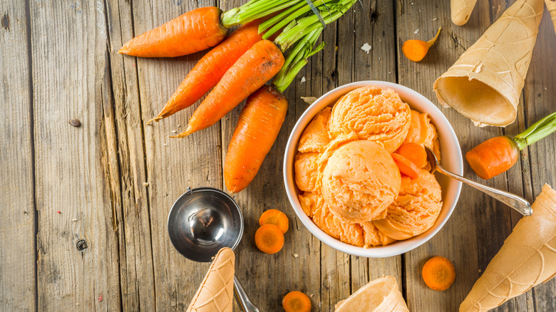 Bowl of carrot ice cream surrounded by carrots