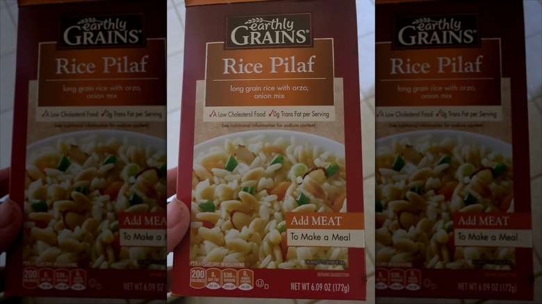 A hand holds a box of Aldi's rice pilaf