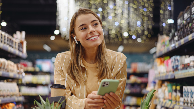 Woman grocery shopping and holding cellphone