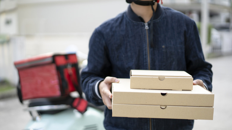 Pizza deliveryman dropping of pizza boxes.