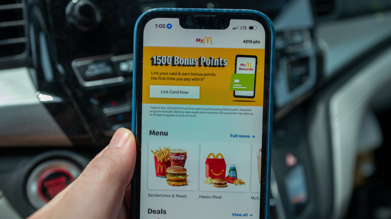 A hand holds up a phone with the McDonald's app open