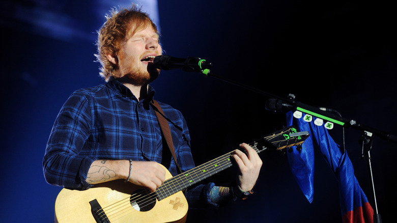 Ed Sheeran singing and playing guitar on stage