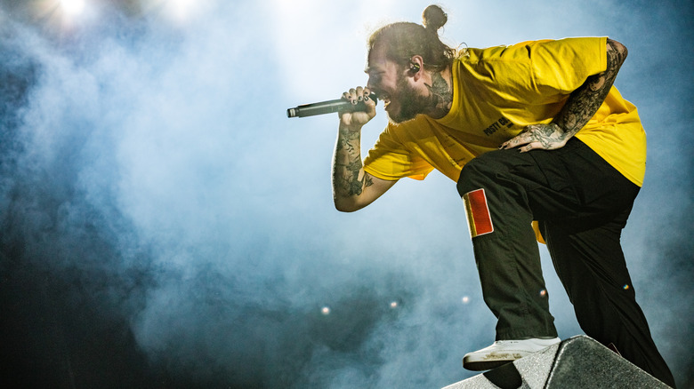 Post Malone singing on stage into a microphone