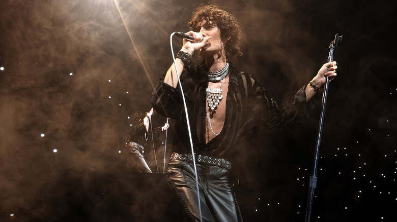 Sombr singing on stage into a standing microphone