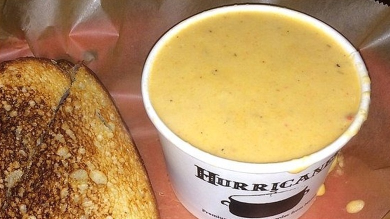 Closeup of a paper cup of Luke's Lobster lobster bisque next to a lobster grilled cheese