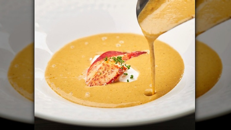 Closeup of a bowl of Truluck's lobster bisque being poured into a white bowl