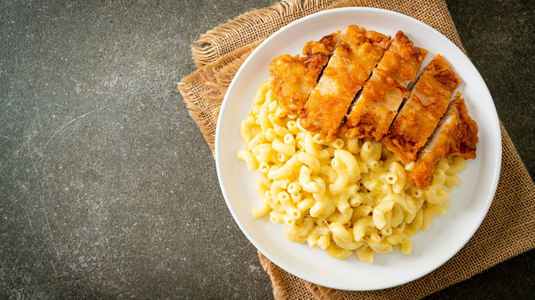 A white plate of mac and cheese with fried chicken