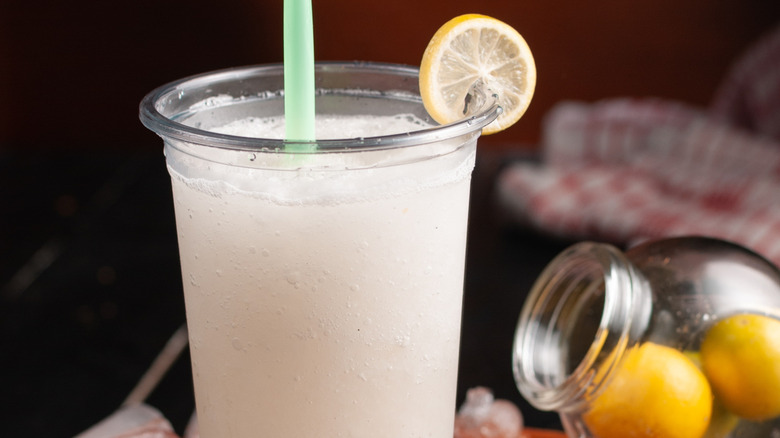 A to-go cup of frosted lemonade with a fresh lemon wheel