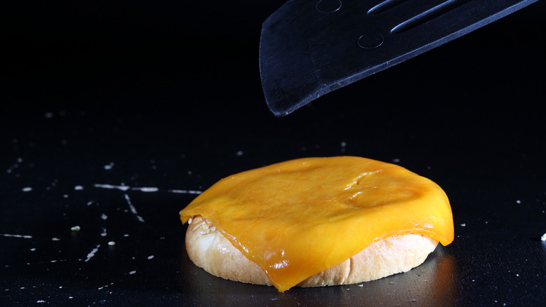 Grilling half of a burger bun with cheese on top