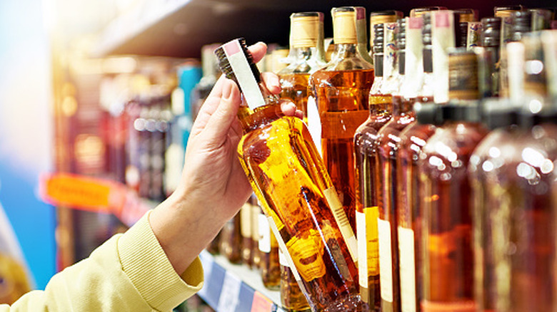 Bottle of whiskey in hand in store