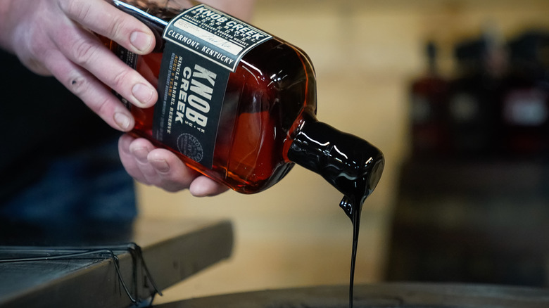 Man sealing the top of a bottle of bourbon with hot wax