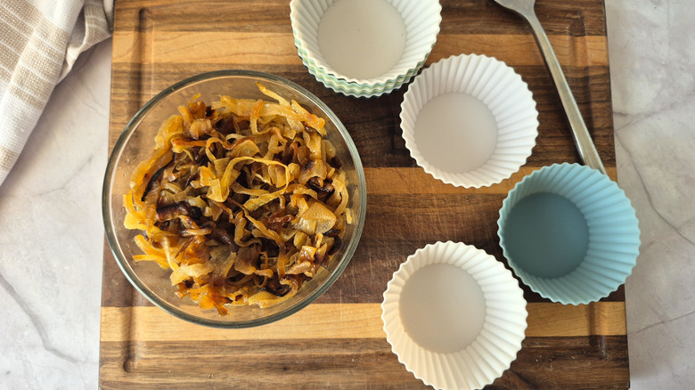a glass bowl of caramelized onions beside silicone muffin cups for portioning