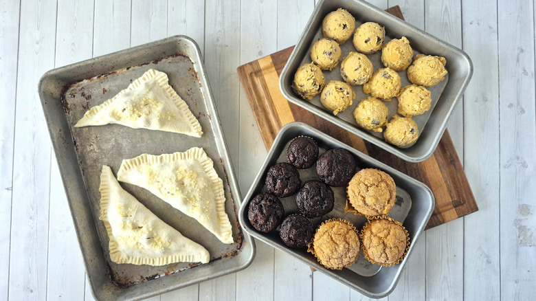 hand pies, cookie dough balls, and muffins portioned on small baking sheets for freezing