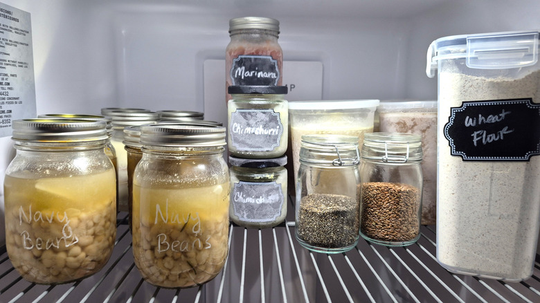 a freezer shelf with sauces, beans, nuts, seeds, stock, and flour stored.