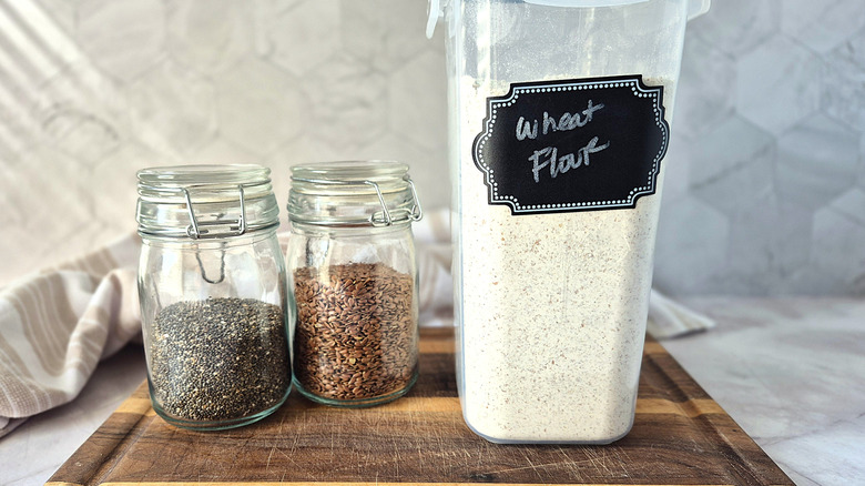 two small jars with chia seeds and flax seed and a plastic bin of wheat flour