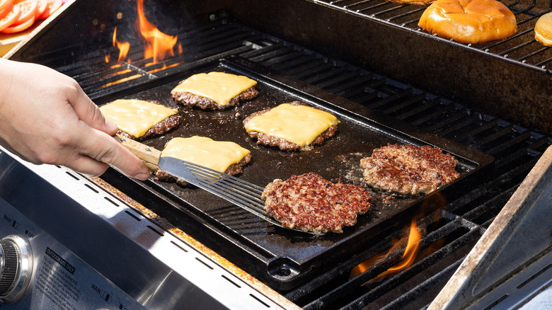 Someone cooks burger patties on a Lodge Cast Iron Reversible Grill/Griddle