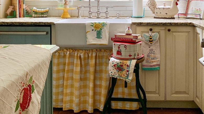 A gingham skirt on a rustic country sink in a cute and cozy country-themed kitchen