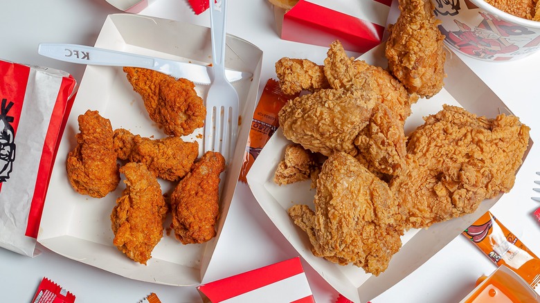 KFC chicken in containers with packaging placed around it on a white table