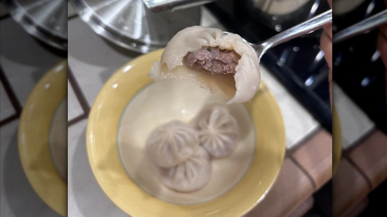 Pork and Shrimp Soup Dumplings by Mila sit in a bowl with one on a spoon