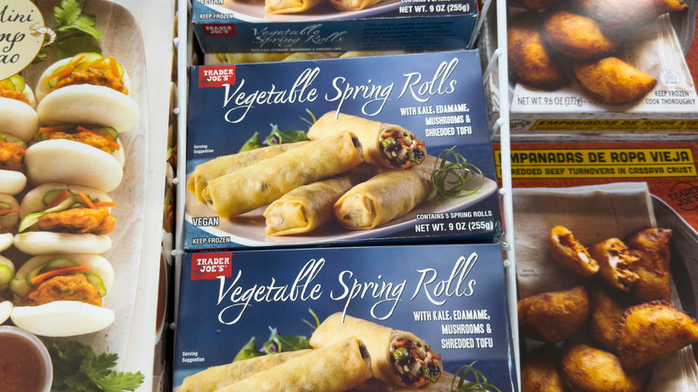 Boxes of Vegetable Spring Rolls by Trader Joe's lie in a grocery display case