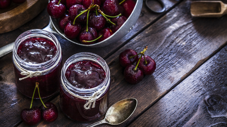 Jars of cherry jam and a bowl of cherries.