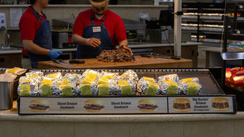 A row of Buc-ee's sandwiches in front of two deli workers.