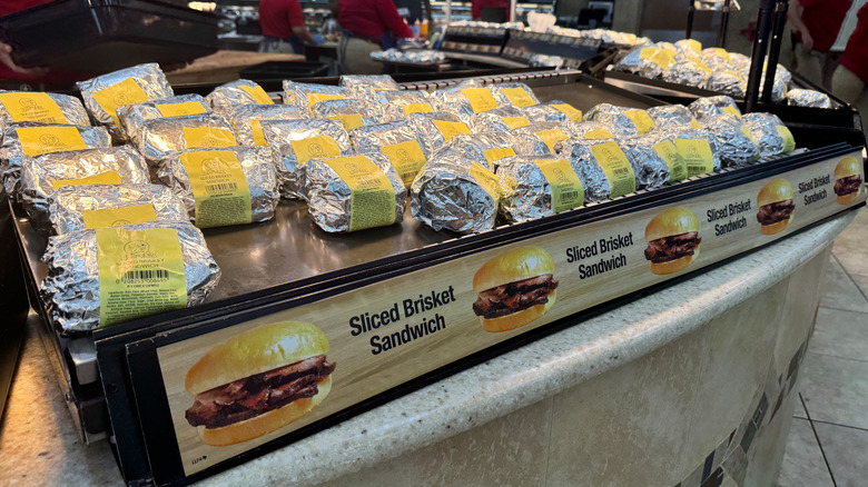 A row of sliced brisket sandwiches under a heat lamp