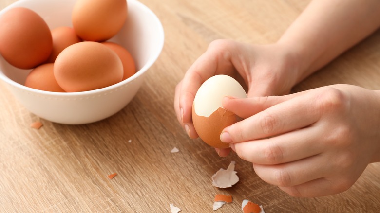 woman peeling a brown hard-boiled egg