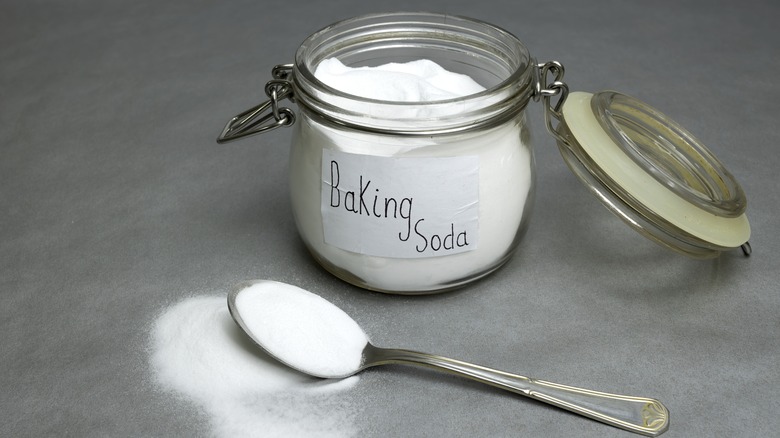 glass jar of baking soda and spoon on gray counter