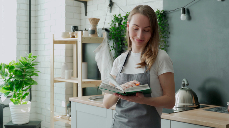 woman reading a cookbook in the kitchen