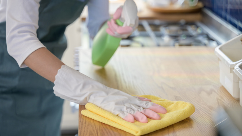 People in kitchen sterilizing kitchen counter with cleaning products