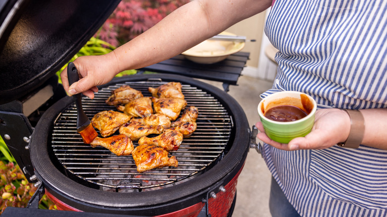 Woman adding sauce to grilled chicken
