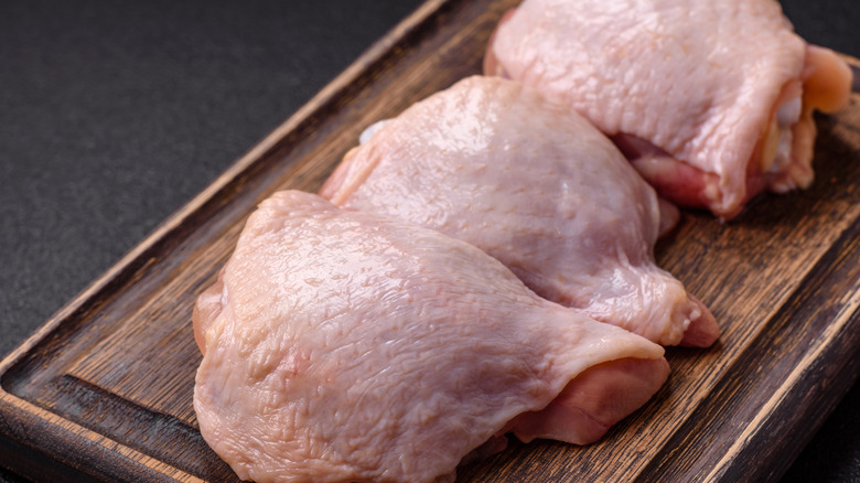 Raw chicken thighs against stone background