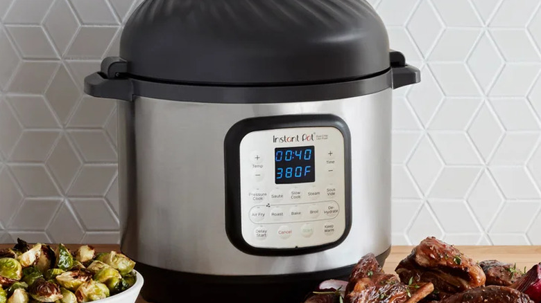 Instant Pot Duo Crisp appliance on countertop behind bowl of brussels sprouts and a bowl of cooked meat