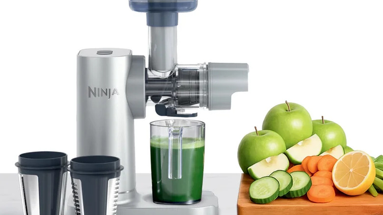 product photo of Ninja Never-Clog 3-in-1 Juicer next to cutting board full of cut fruit and vegetables
