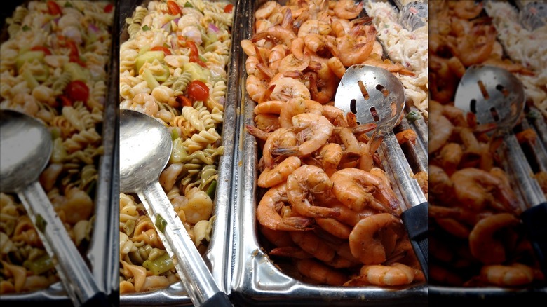 Tray of pasta salad and a tray of shrimp at a seafood buffet