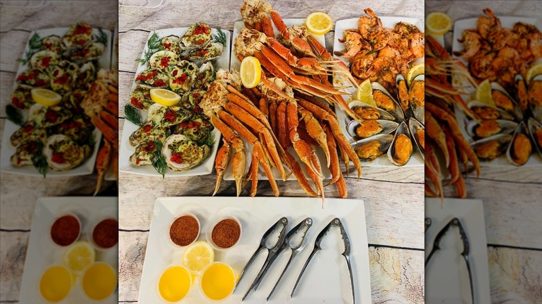 A huge display of cooked seafoods on plates with tubs of melted butter and sauce