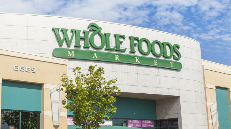 Whole Foods Market storefront with a tree in front and a clear blue sky overhead