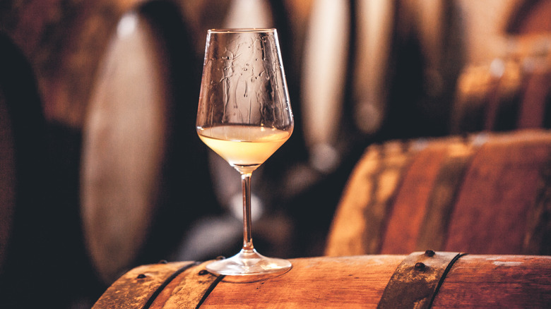 A glass of white wine on a wooden barrel