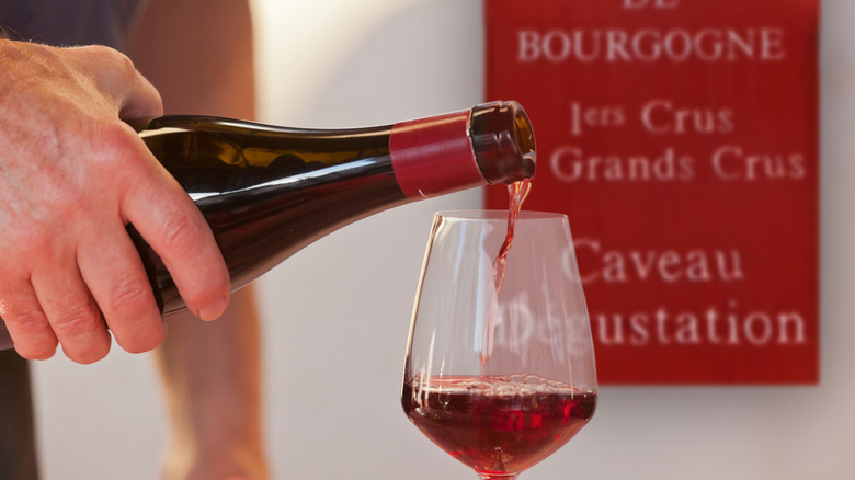 A glass of red wine vb being poured into a glass