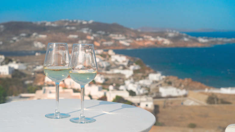 Two glasses of white wine on a table in Greece with the sea in the background