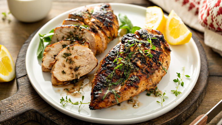 Plate of grilled chicken breast with lemon and herbs