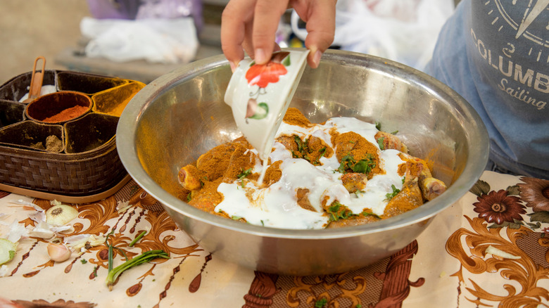 Marinating a bowl of chicken in yogurt and spices