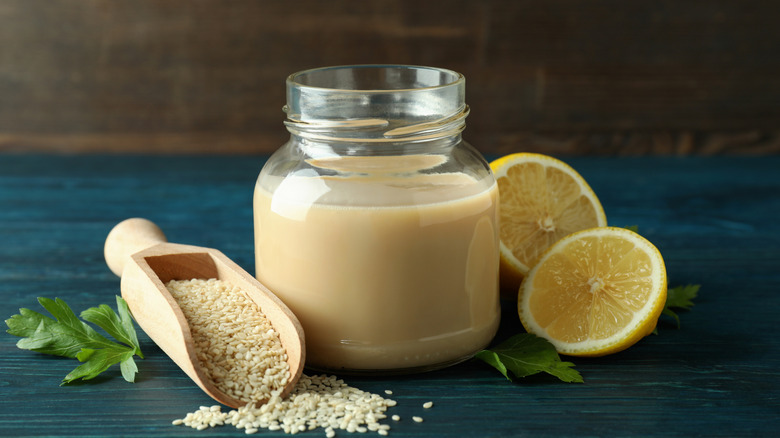 tahini paste with lemon and sesame seeds on blue countertop