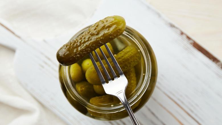 Pickle on a fork above a jar of pickles