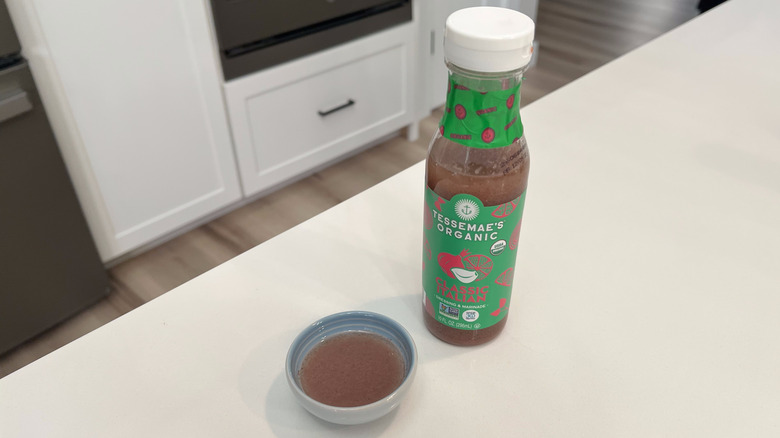 A bottle of Tessemae's Organic Classic Italian sitting on a white kitchen counter next to a small condiment dish filled with the dressing