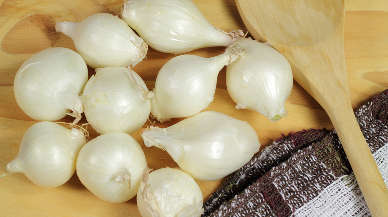 Peral onions and wooden spoon on wood table