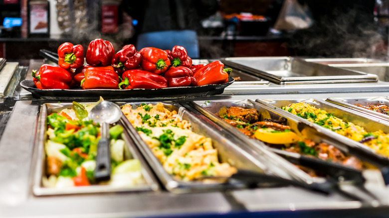steam table with assorted dishes and fresh red peppers