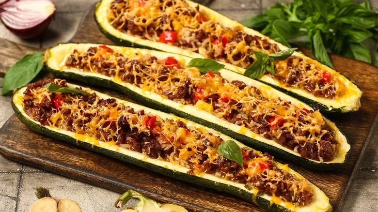 three zucchini boats with cheese on a wooden board