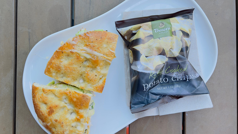 Hot Panera sandwich with a bag of chips on a plate